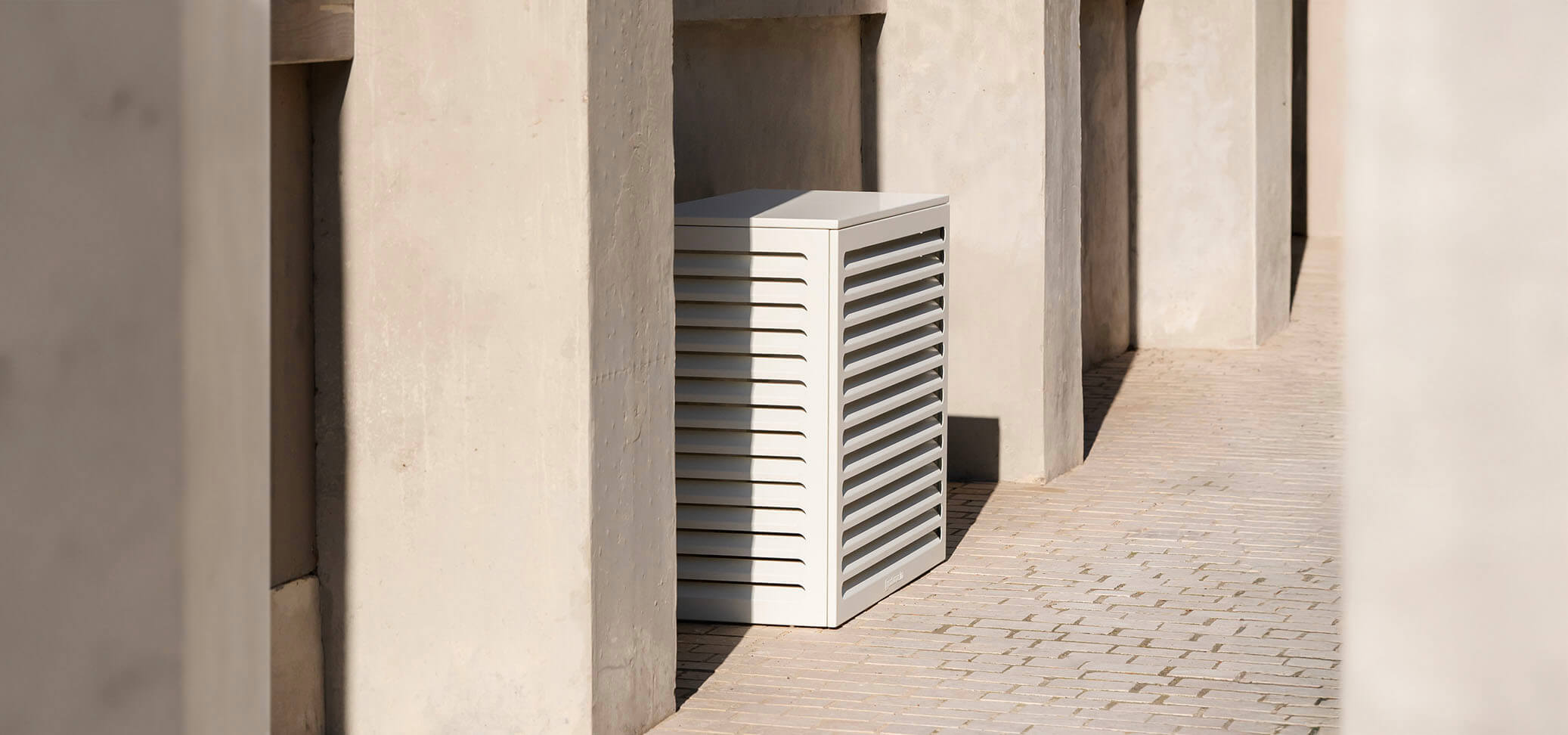 Cache clim blanc sur un fond de mur en béton, dans un style très architecte