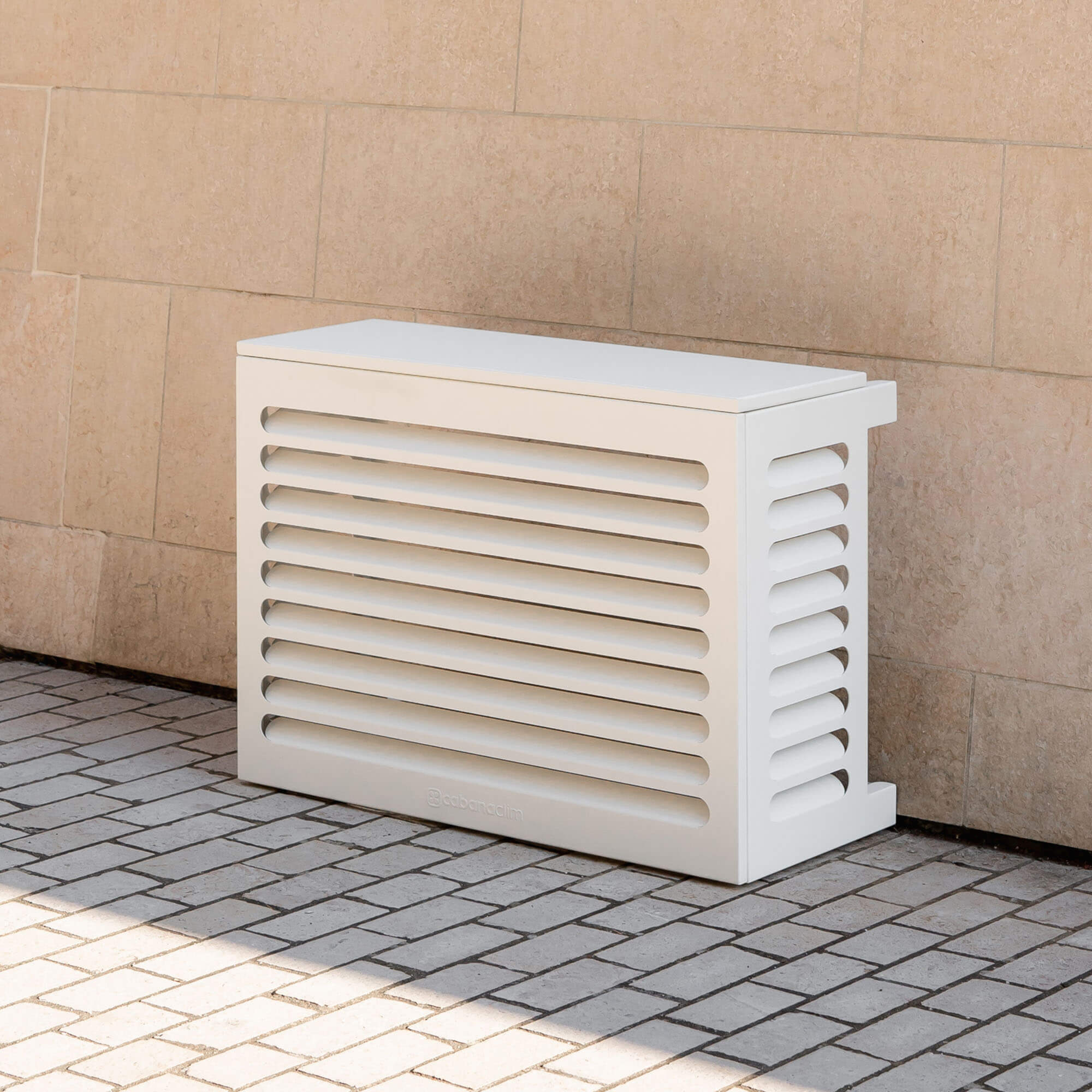Cache clim blanc (RAL 9010) pour climatiseur ou pompe à chaleur – taille XS – vue de face extérieure sur fond de mur clair, design contemporain en aluminium, persiennes pour ventilation optimale