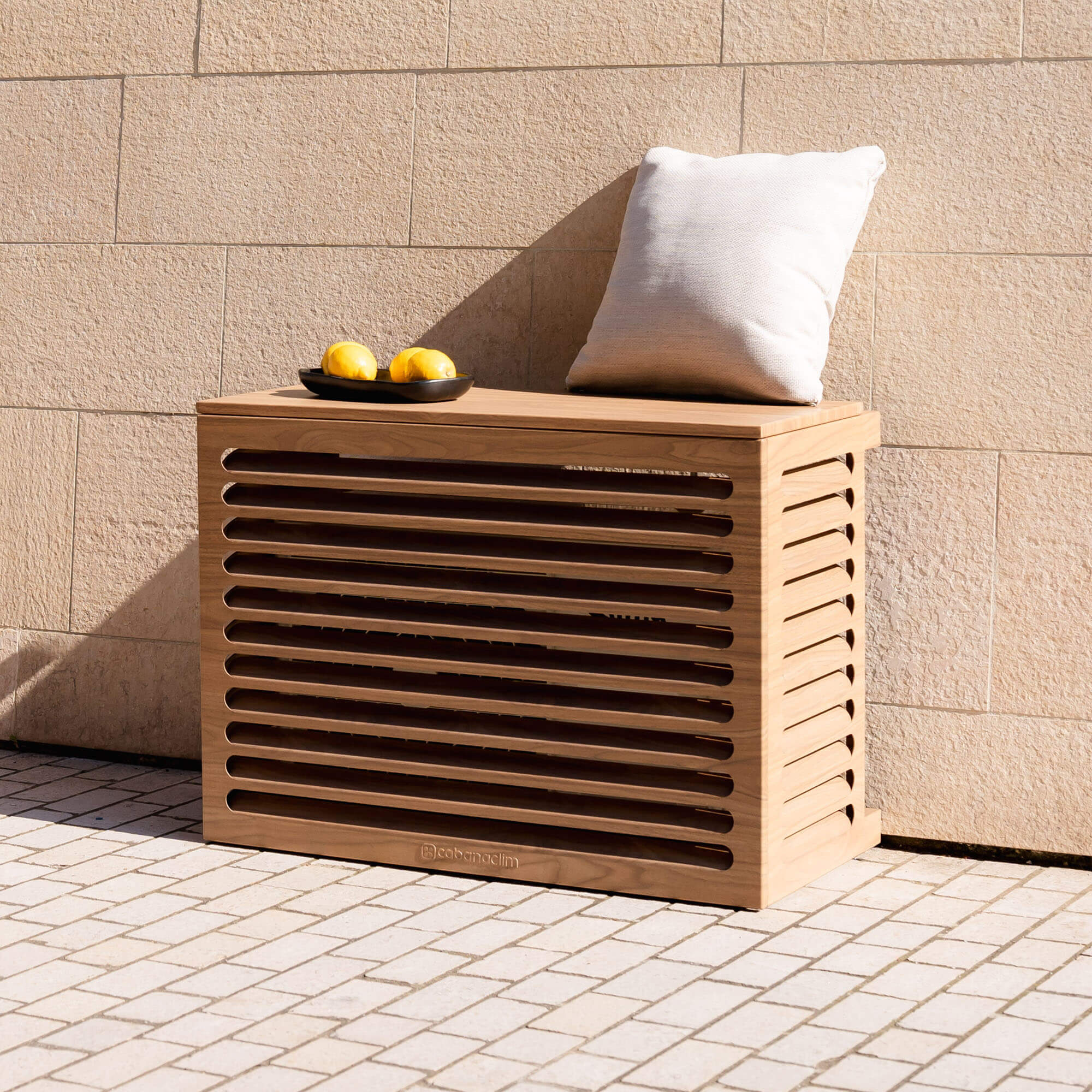 Modèle cache clim bois exotique – taille S – vue : vue de face avec déco. Structure ventilée et design, idéale pour sublimer une façade ou un jardin. Un rendu soigné qui allie déco et performance.