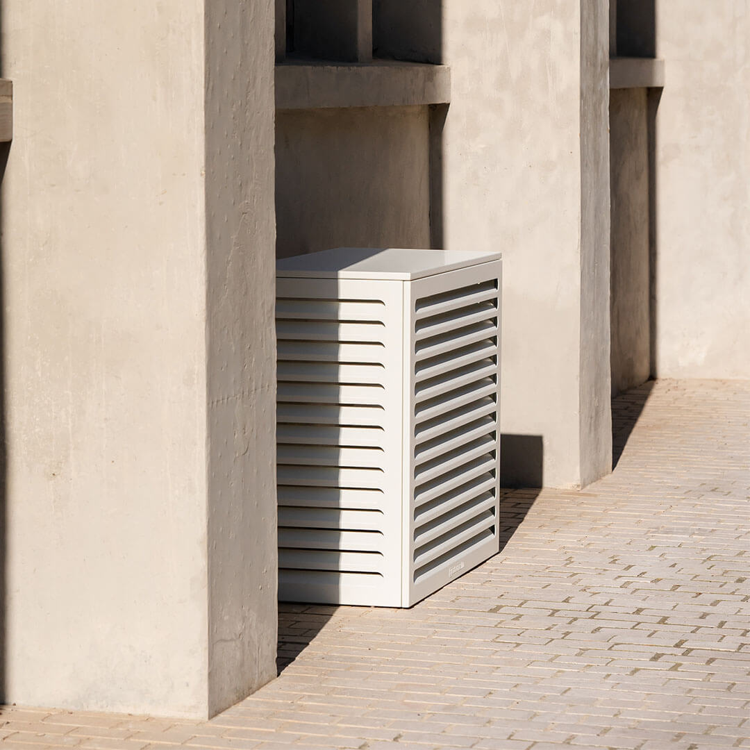 Cache clim blanc épuré Cabanaclim intégré dans un décor minéral chic, entre colonnes béton et sol en briques.