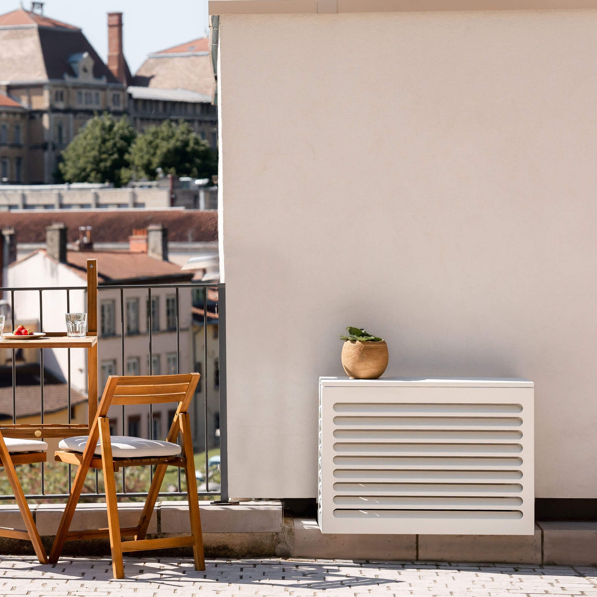Cache clim gris anthracite (RAL 7016) Cabanaclim – taille XS – posé dans un environnement extérieur aménagé. Idéal pour dissimuler une unité extérieure dans un espace déco avec plantes, mobilier outdoor et ambiance architecturale.