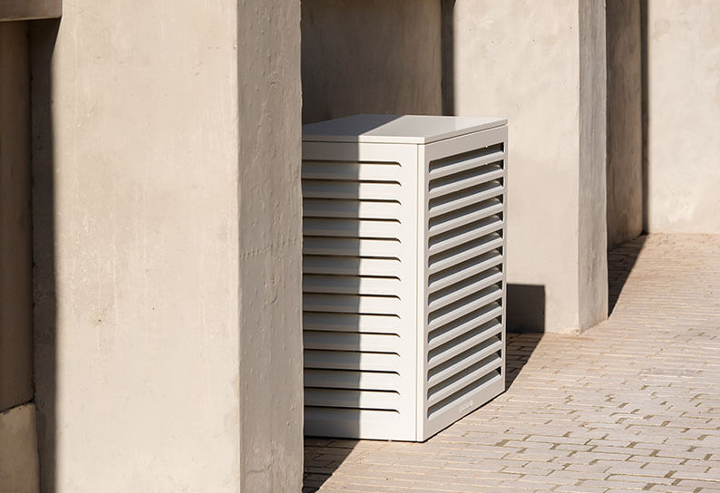 Cache clim Cabanaclim blanc taille S installé entre deux murs dans une cour moderne ensoleillée