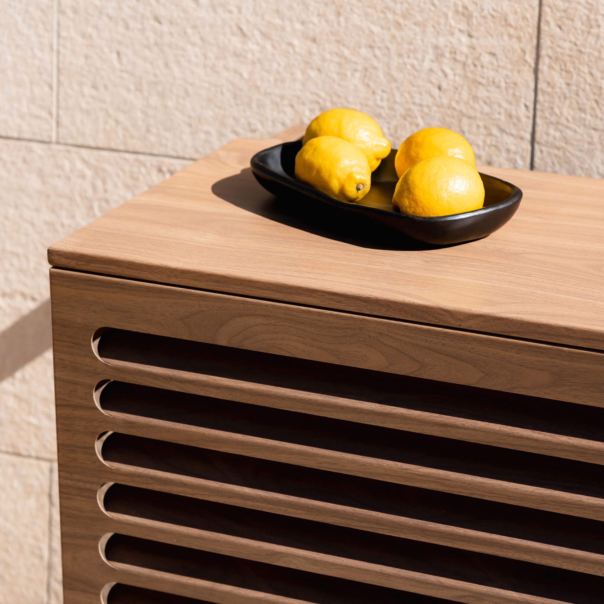 Cache clim bois chêne Cabanaclim – zoom avec citrons dans un plat. Finition aluminium aspect bois, parfaite pour intégrer une unité extérieure de climatisation ou pompe à chaleur dans un environnement chaleureux, naturel et esthétique.