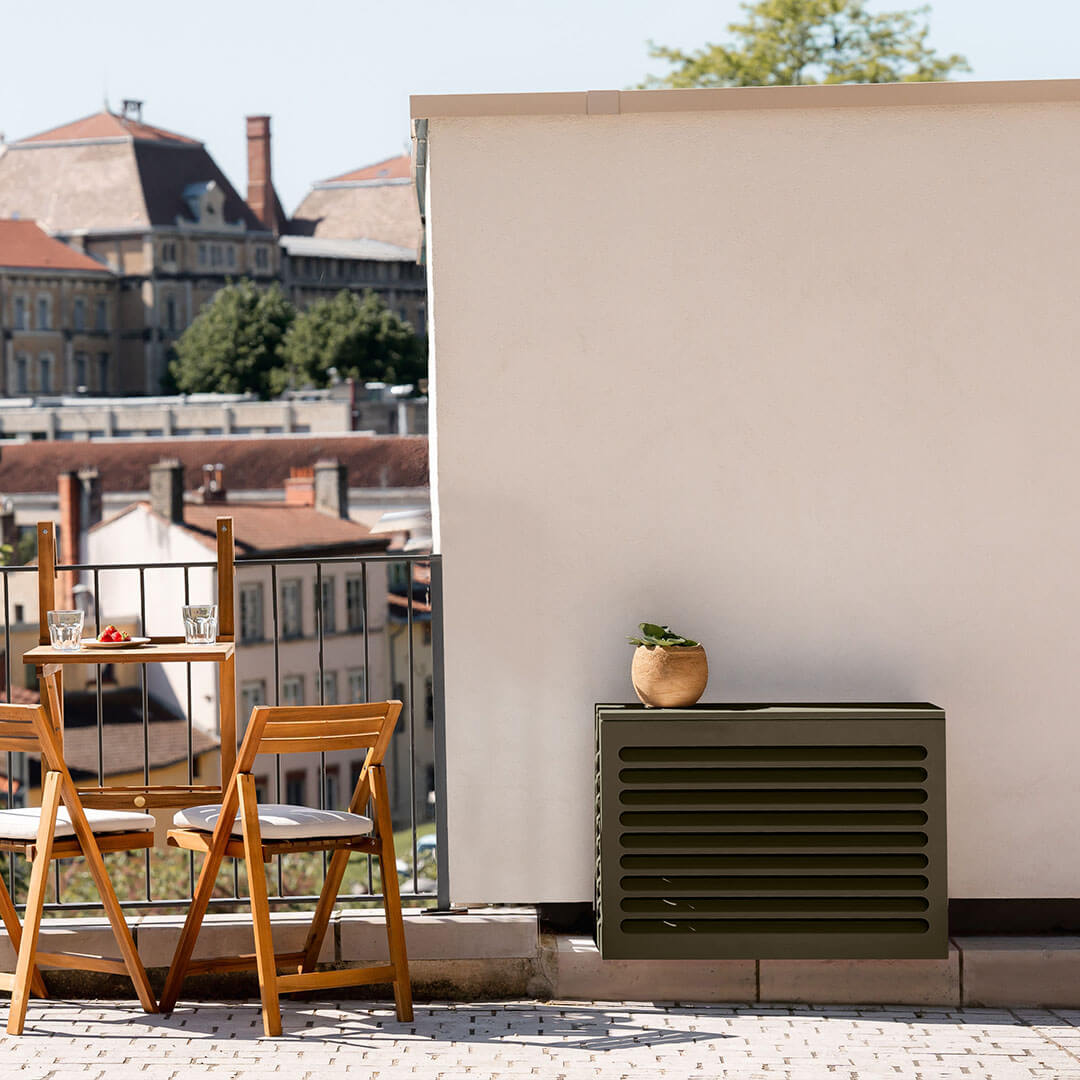 Cache clim vert olive (RAL 6014) Cabanaclim – taille XS – vue de face avec déco. Protection élégante et durable, pensée pour s’intégrer à tous les environnements extérieurs. Un rendu soigné qui allie déco et performance.
