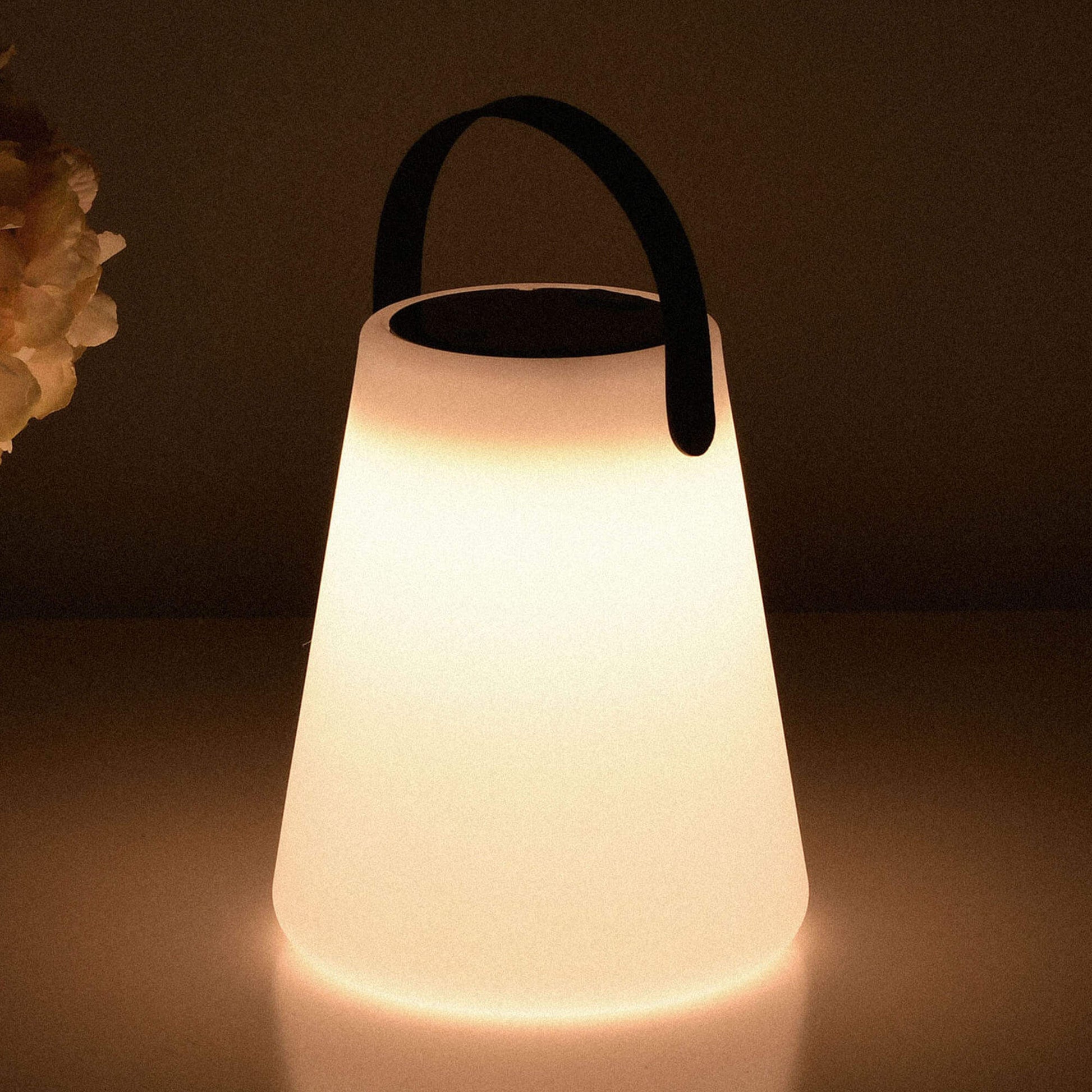 Lampe solaire d’extérieur allumée dans l’obscurité, avec poignée noire, lumière chaude diffuse